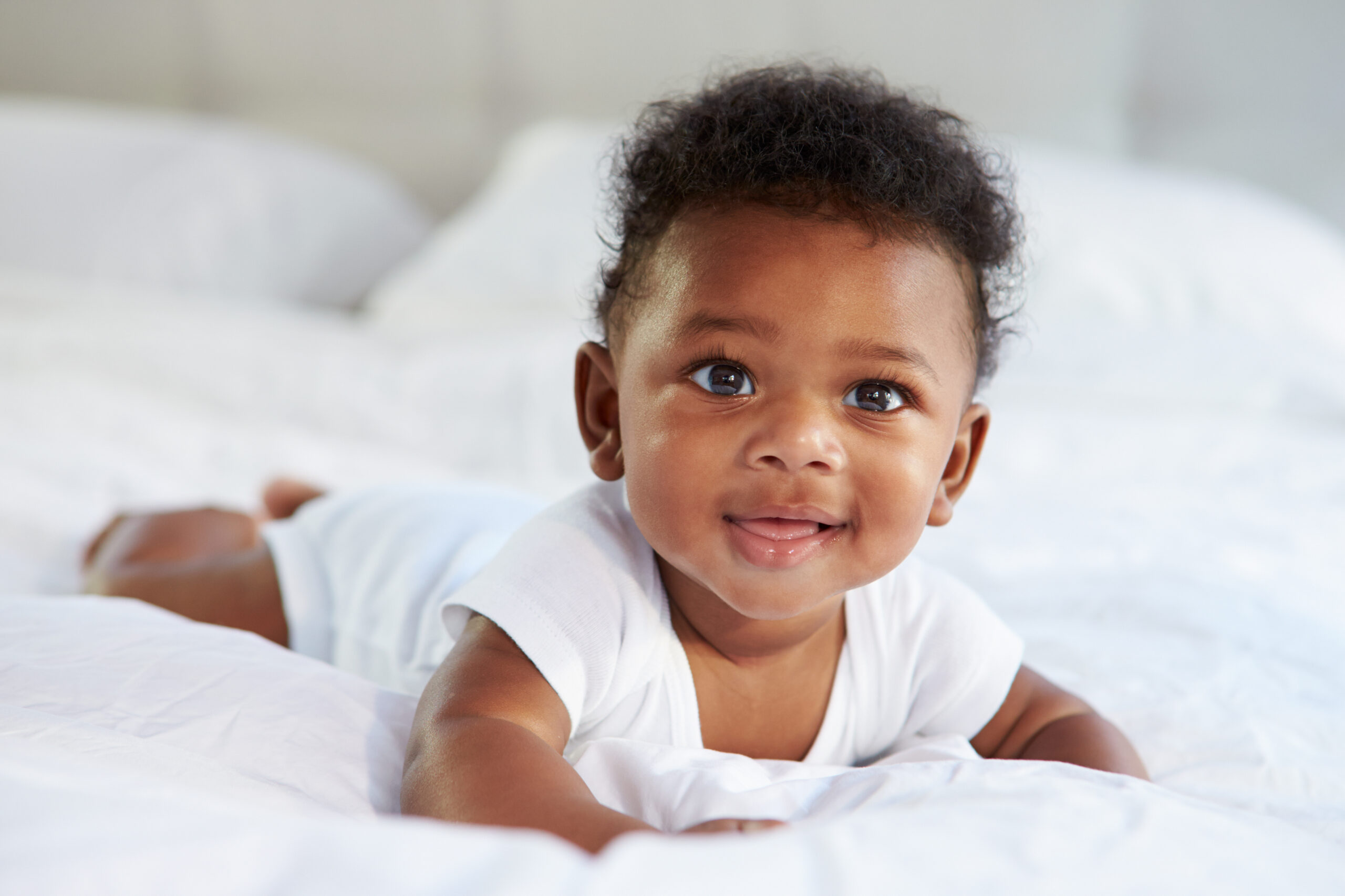 Cute Baby Lying On Tummy In Parent's Bed